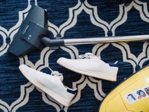 Picture of sneakers and a vacuum cleaner on blue carpet