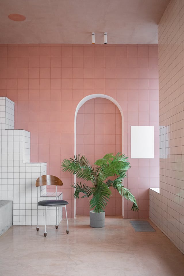 Rose pink tile wall serves as the focal point in bathroom. Other walls contrast with white square ceramic.